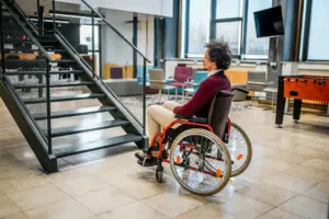 A person in a wheel chair looking at the stairs.