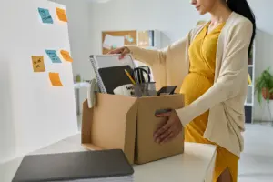 A pregnant woman gathering her belongings in a box.