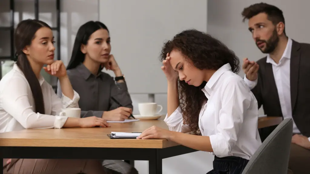 A group of workers looking at their female coworker with hate.
