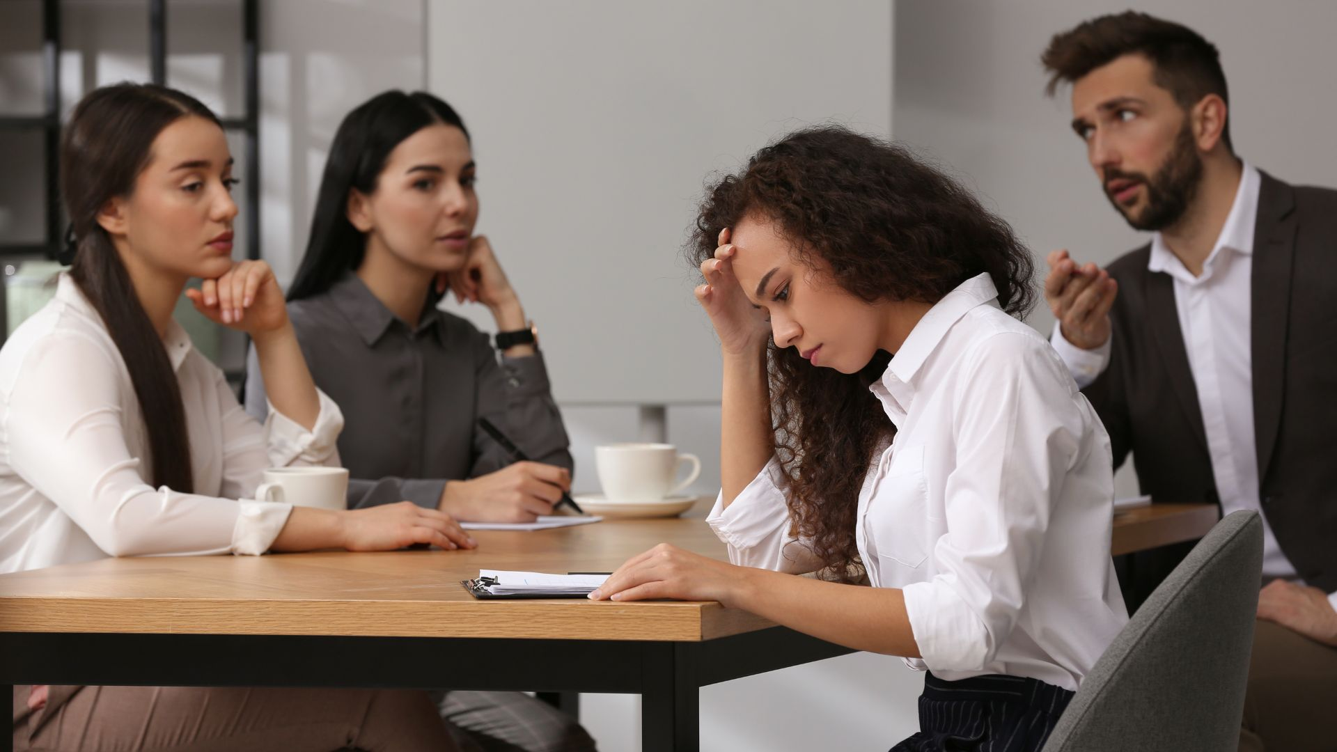A group of workers looking at their female coworker with hate.