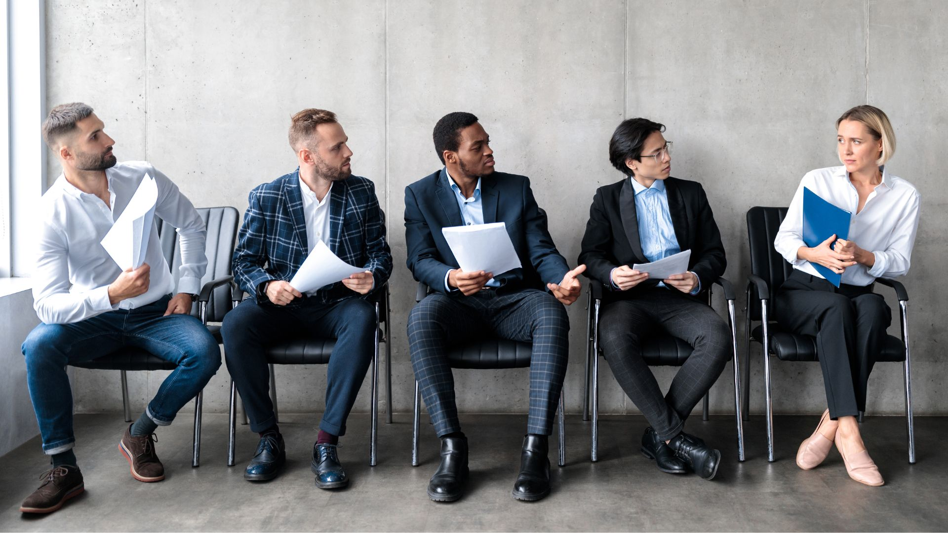 A row of male applicants staring at a woman with disdain.
