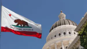 A closeup of the California state flag and the capital building.