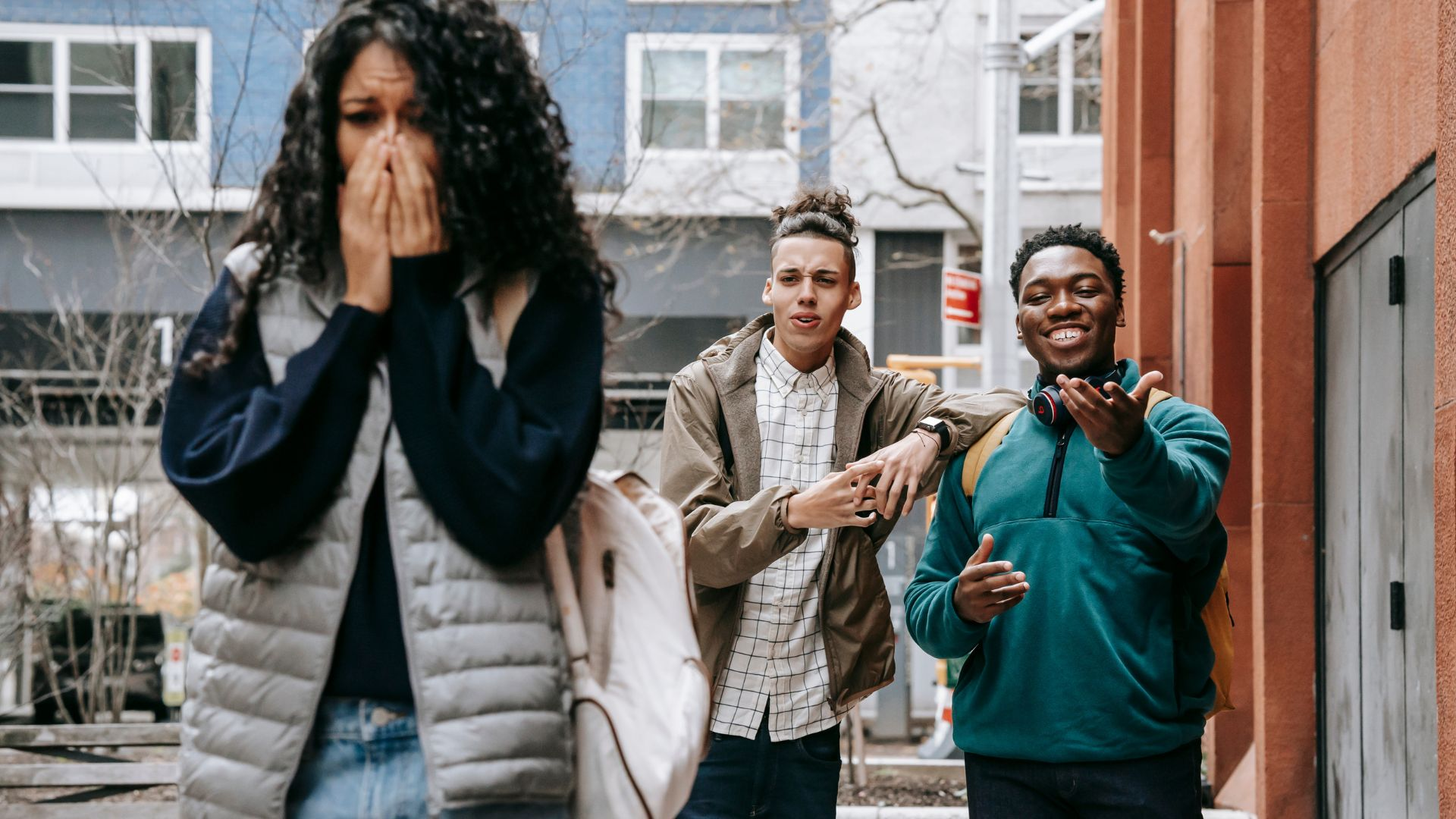A crying woman walking away after getting verbally harassed by two guys.