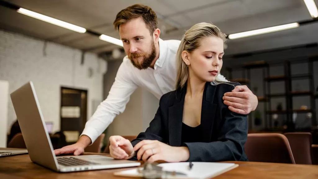 A man sexual harassing a female coworker.