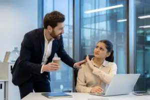 A man offering a drink to a female coworker who doesn't want it.