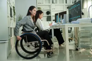 A woman in a wheelchair struggling to move away from her desk.