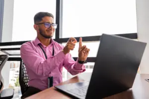 A deaf man explaining something to his coworkers through a video chat.