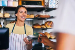 A female cashier at a bakery ringing up a customer.