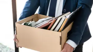 A fired man carrying a box of his stuff.