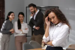 A group of workers shunning a colored coworker behind her back.
