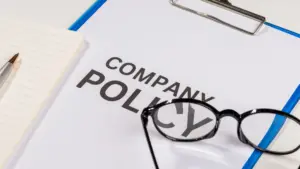 A clipboard with a Company Policy paper with a pair of glasses.