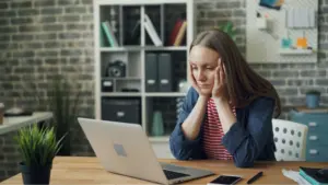 A woman looking stressed at a laptop.