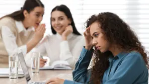 Two white coworkers talking behind a black coworkers back.