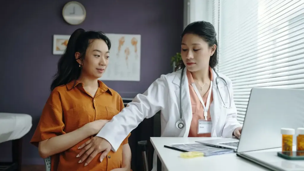 A doctor touching a pregnant woman's stomach.