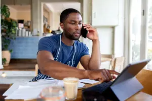 A coffee shop worker on the phone and looking at tablet.