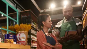 Two grocery store workers looking at an ipad.