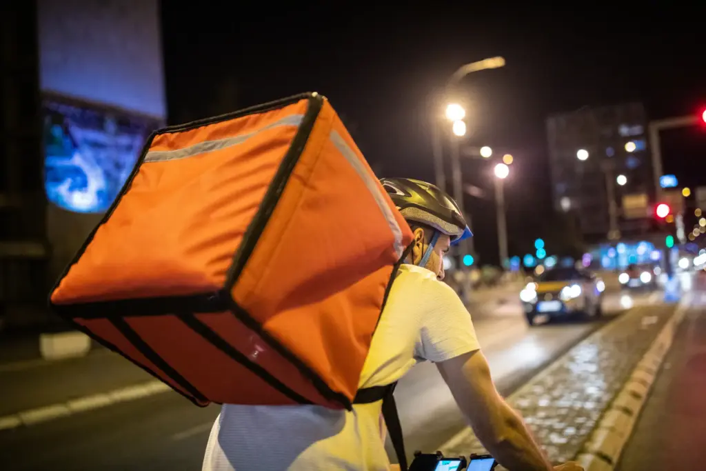 A person delivering food on a bike at night.