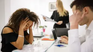 A woman looking stressed while surrounded by her coworkers.