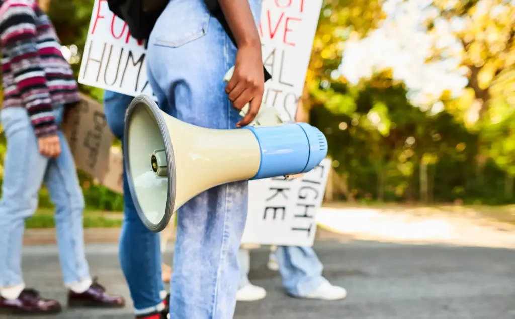A person holding a megaphone at a protest and excercising their right of free speech.