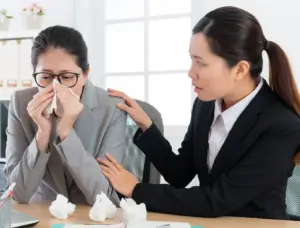An office worker checking on her sick coworker.