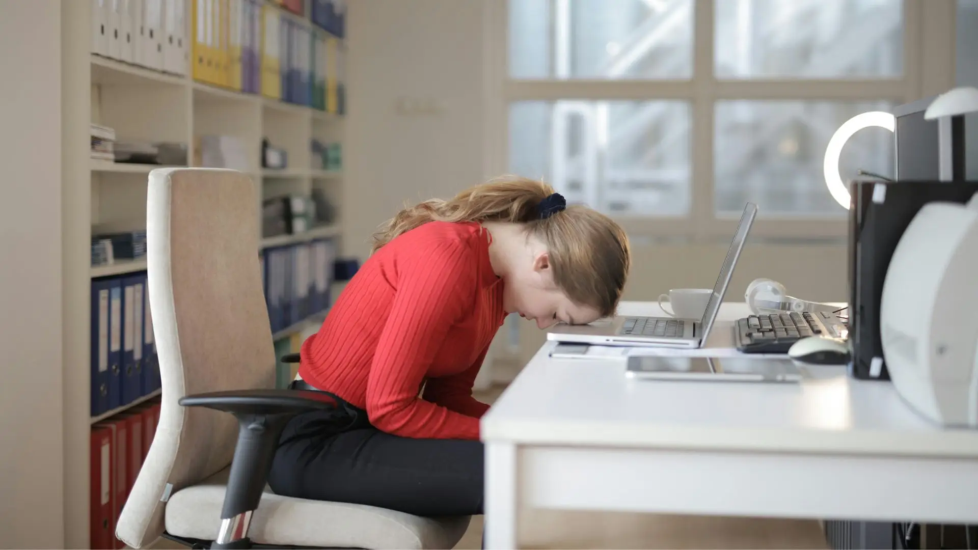A miserable worker putting her head on her desk.