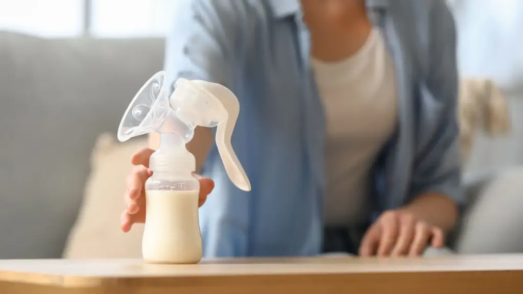 A working mom reaching for a breast pump on the table.