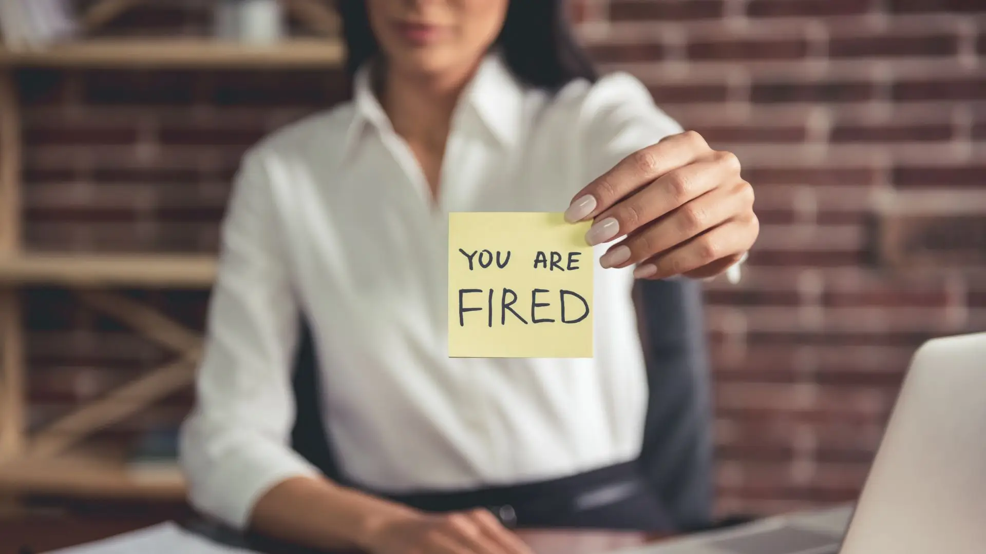 A boss telling her employee that they are fired through a sticky note.