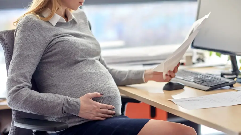 A pregnant worker holding onto her stomach.