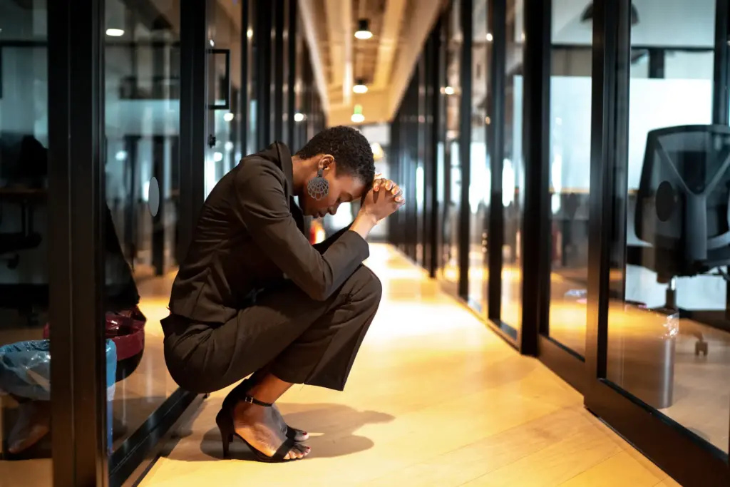 A woman kneeling down with stress at her work.