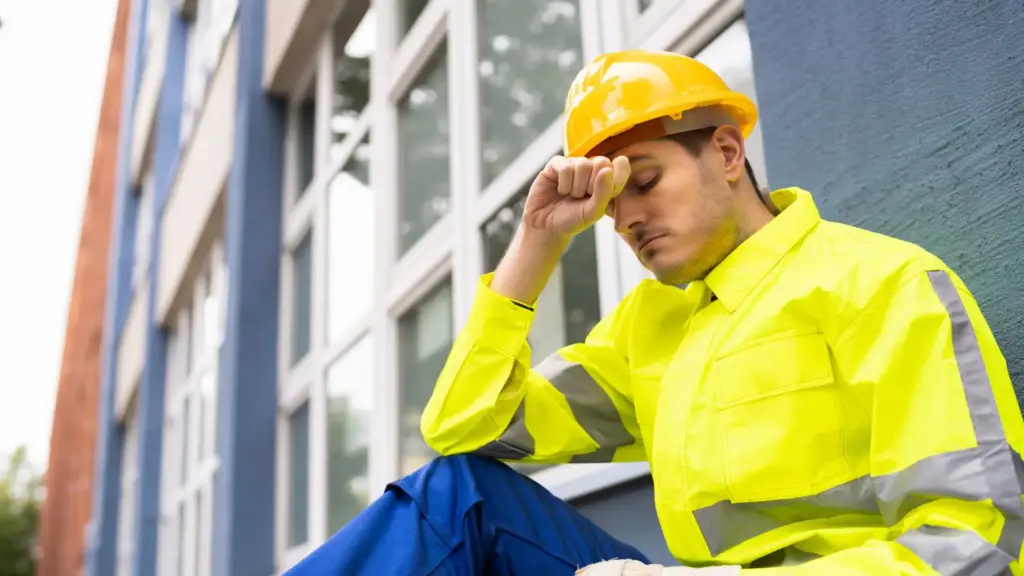 A sad construction worker stressing about not getting any health insurance from his job. 