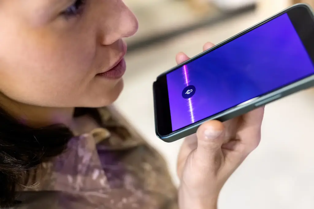 A woman recording her voice on her phone. 