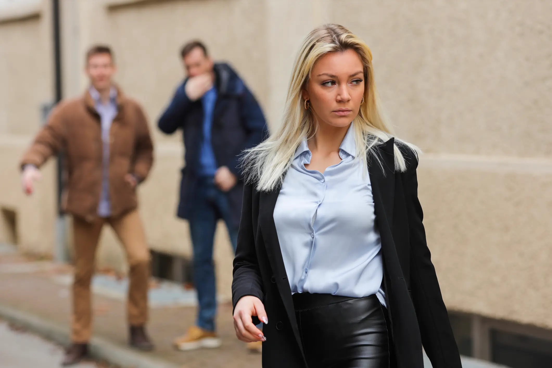 Two men staring and making suggestive gestures at a woman walking away.