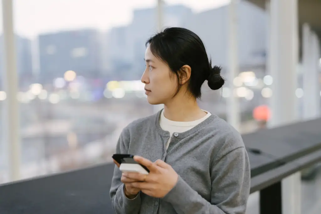 A woman on her phone looking aimless after suffering workplace harassment. 