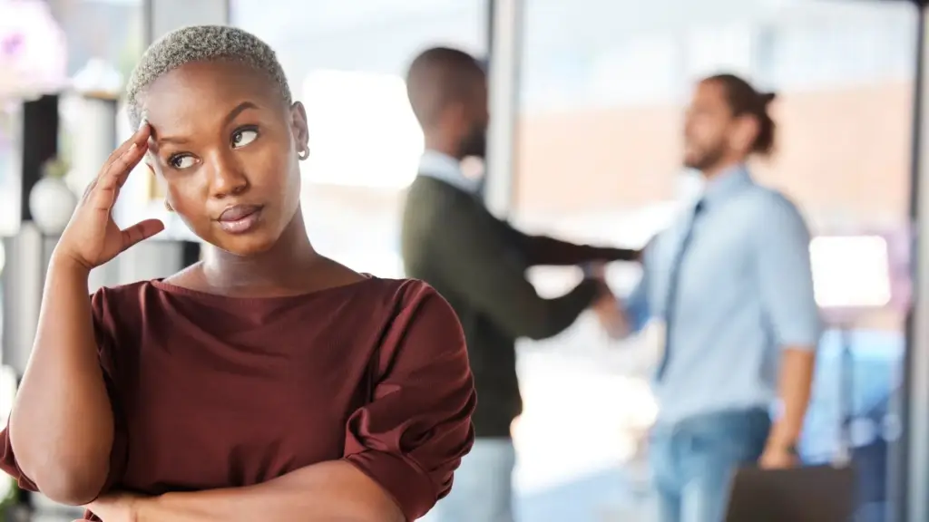 A woman looking annoyed while her supervisor is giving preferred treatment to another coworker. 