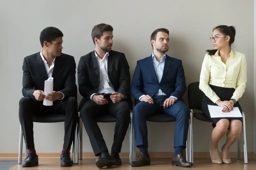 A group of men looking at a woman in disgust while waiting for a job interview.